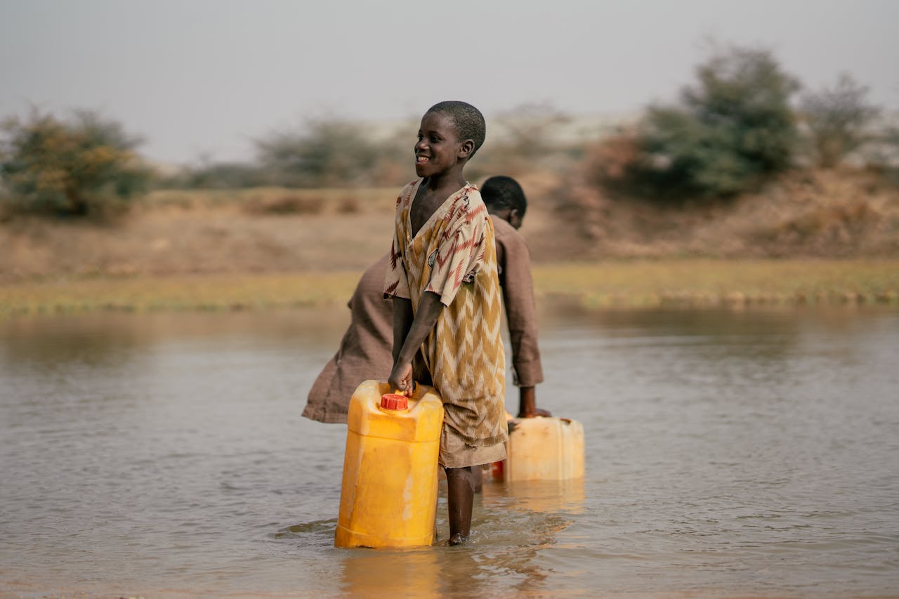 Boys wading through water to collect jerrycans